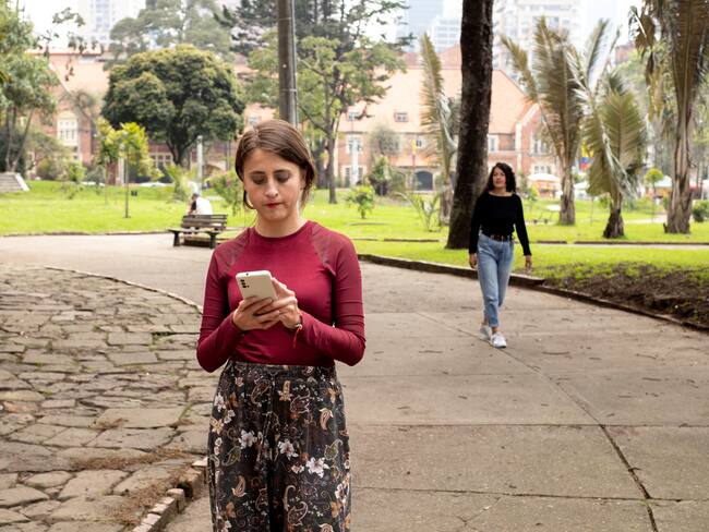 Mujer caminando y navegando en el celular (Vía Getty Images)