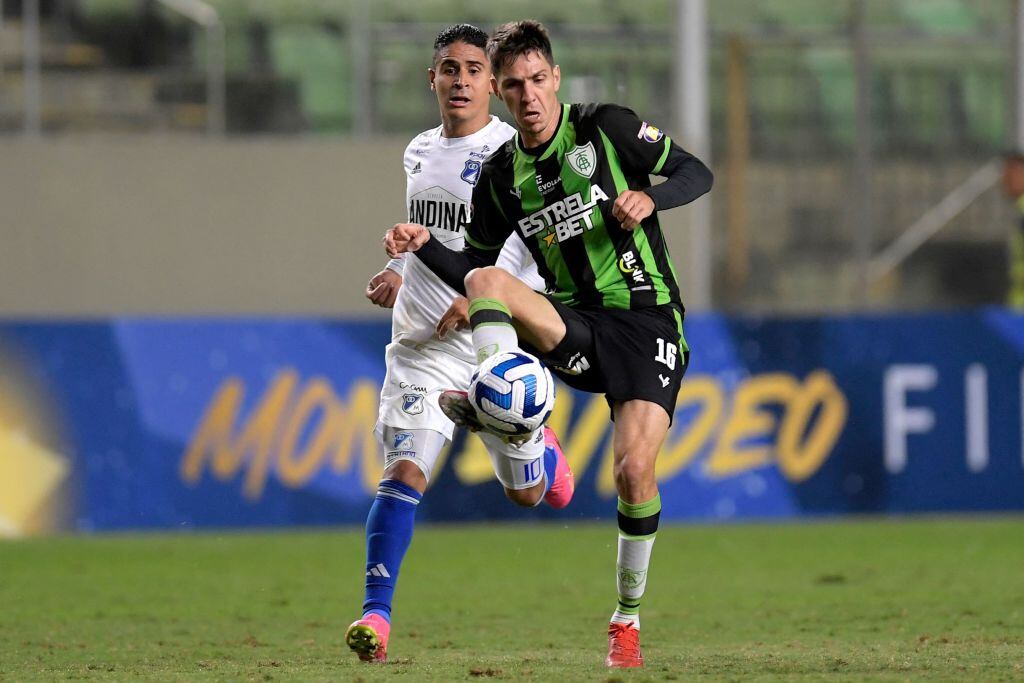 Al fondo y de blanco, Daniel Cataño, jugador de Millonarios. Al frente y de verde, Alexandre Egea, jugador de América Mineiro. 6 de junio de 2023 Copa Sudamericana. Foto: DOUGLAS MAGNO/AFP via Getty Images.