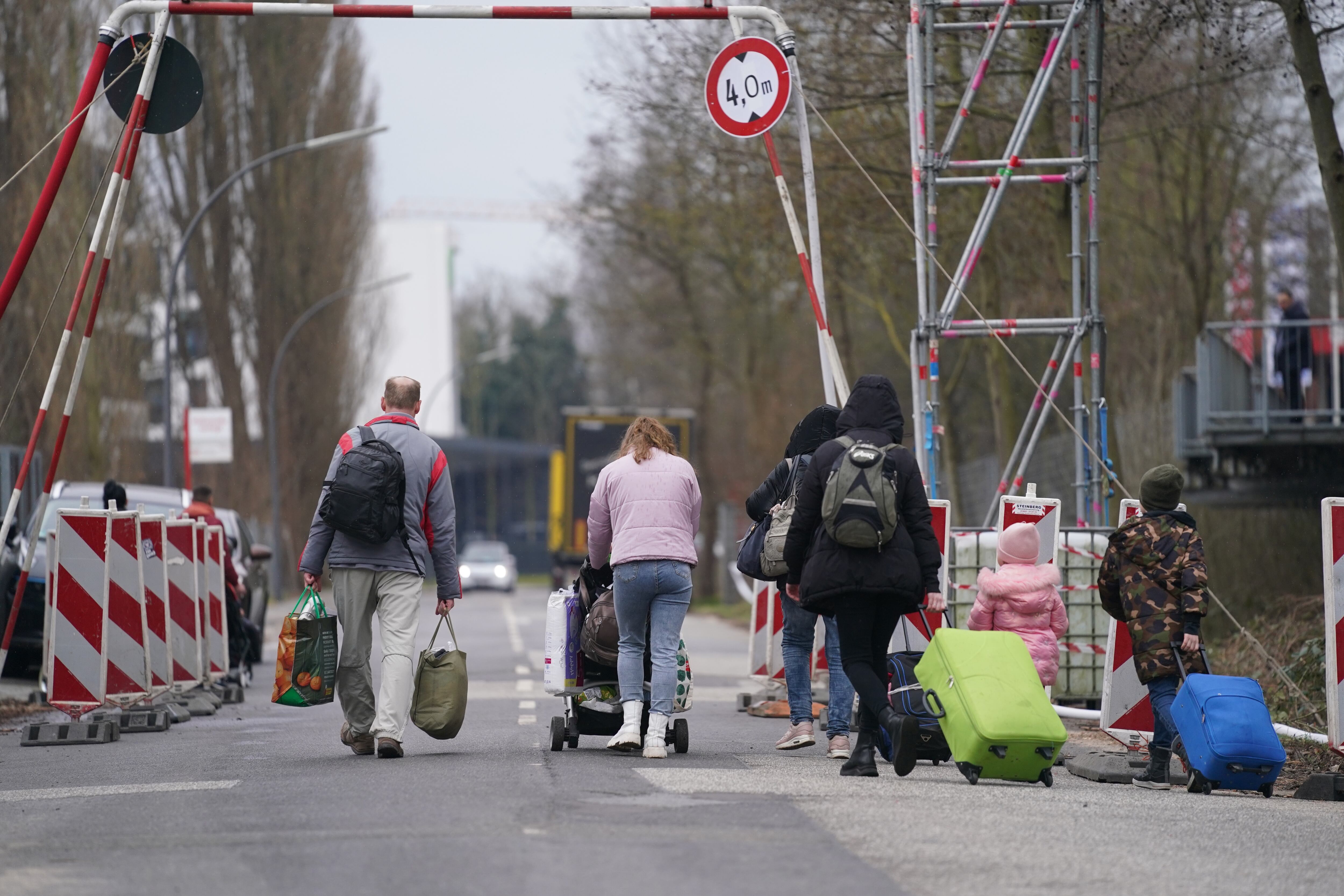 14 March 2022, Hamburg: Ukrainian refugees leave the refugee shelter in the former Fegro wholesale market in the Harburg district with their luggage. Photo: Marcus Brandt/dpa (Photo by Marcus Brandt/picture alliance via Getty Images)