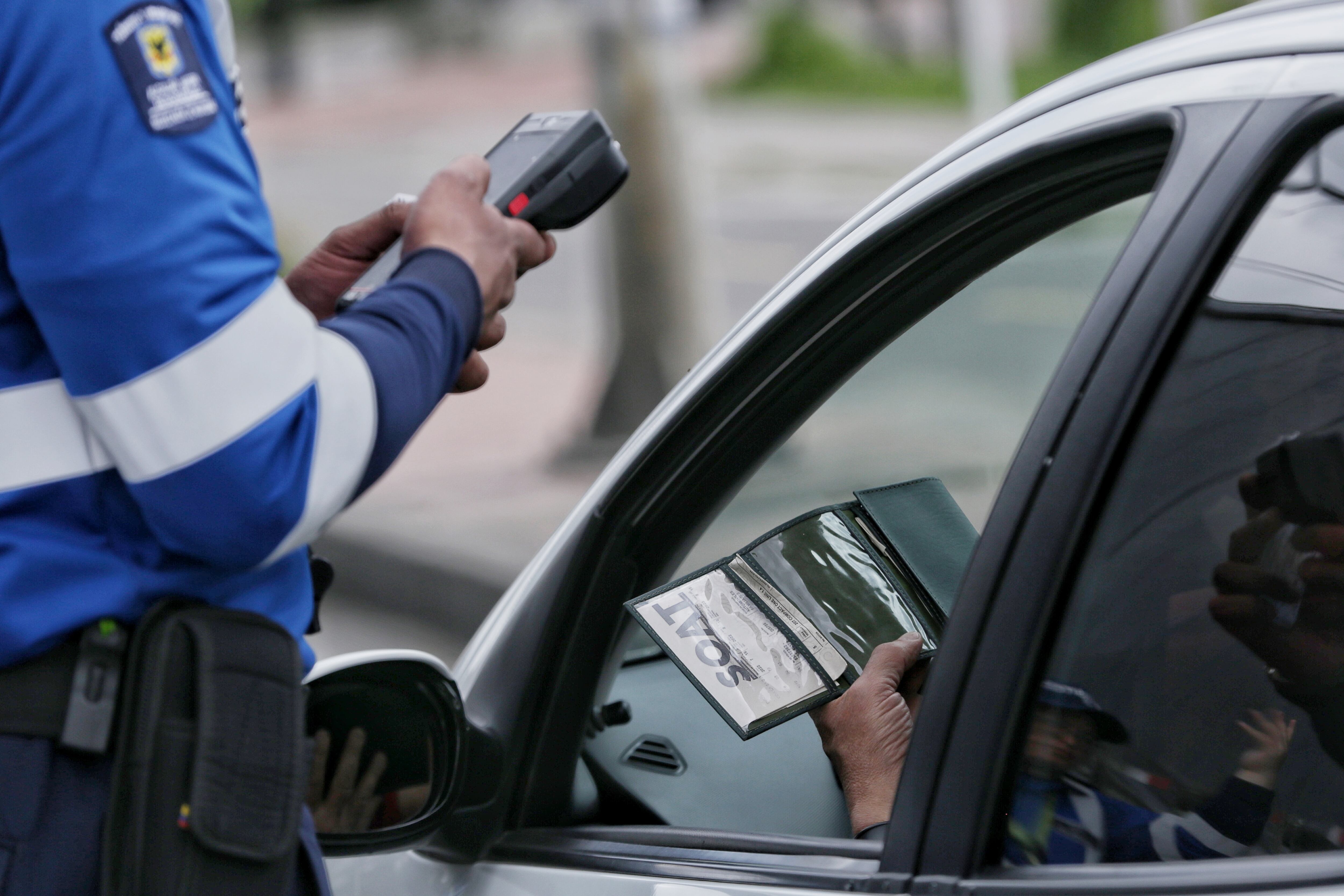 Agente Civil de Tránsito revisando que la documentación vehicular esté vigente (Foto vía Colprensa)