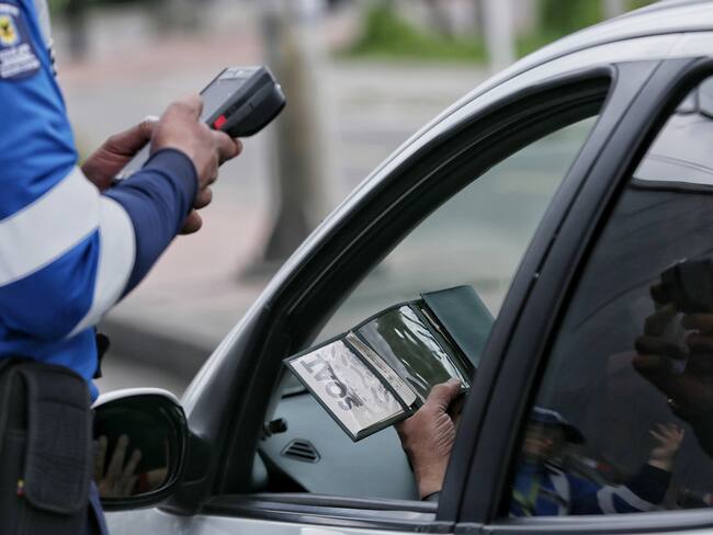 Agente Civil de Tránsito revisando que la documentación vehicular esté vigente (Foto vía Colprensa)
