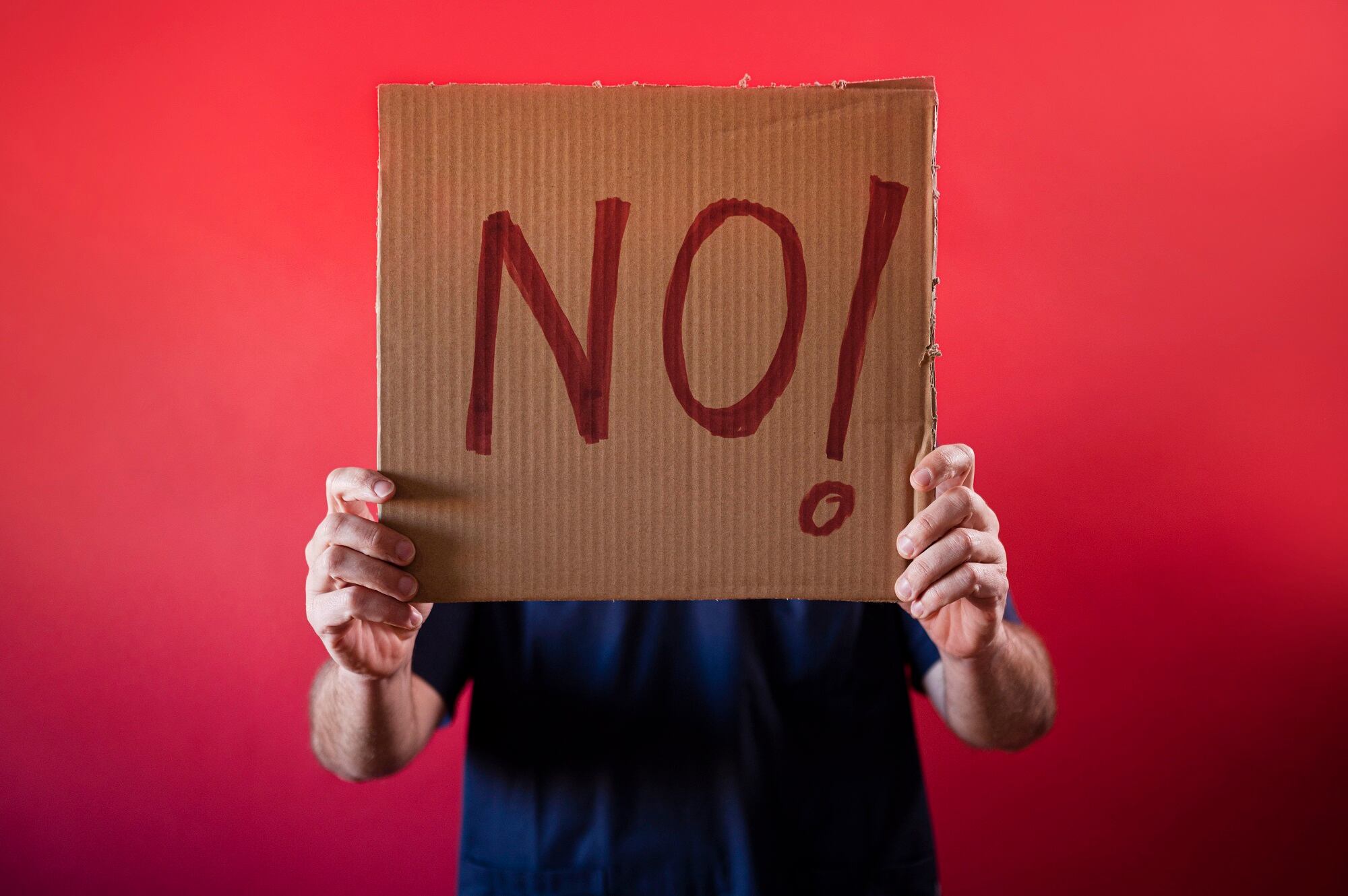 Doctor holding a cardboard sign that says NO!.