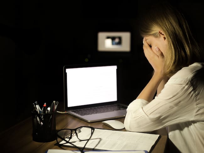 Depressed woman working with computer at night