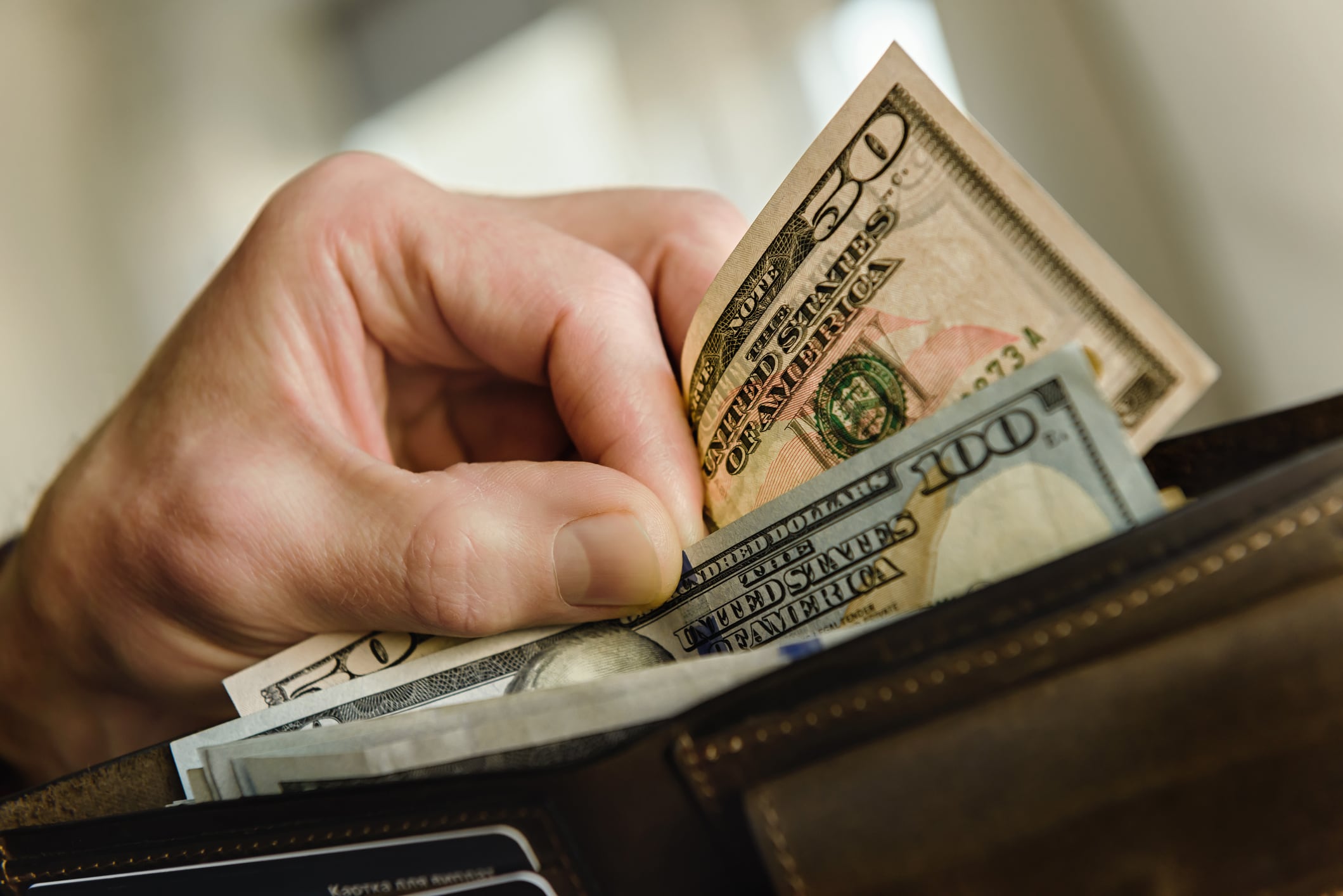 Hombre sacando de su billetera dólares estadounidenses (Getty Images)