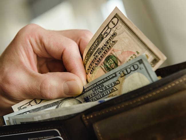 Hombre sacando de su billetera dólares estadounidenses (Getty Images)
