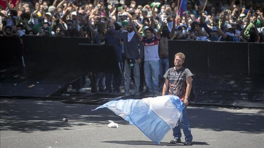 Un manifestante sostiene una bandera argentina durante una protesta contra las reformas a las pensiones propuestas por el Gobierno, durante una marcha hacia el Congreso Nacional Argentino. Foto: Agencia Anadolu