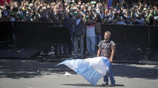 Un manifestante sostiene una bandera argentina durante una protesta contra las reformas a las pensiones propuestas por el Gobierno, durante una marcha hacia el Congreso Nacional Argentino. Foto: Agencia Anadolu