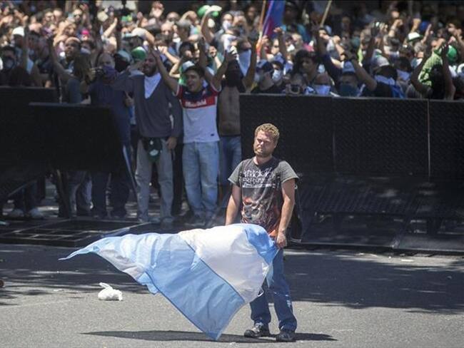 Un manifestante sostiene una bandera argentina durante una protesta contra las reformas a las pensiones propuestas por el Gobierno, durante una marcha hacia el Congreso Nacional Argentino. Foto: Agencia Anadolu