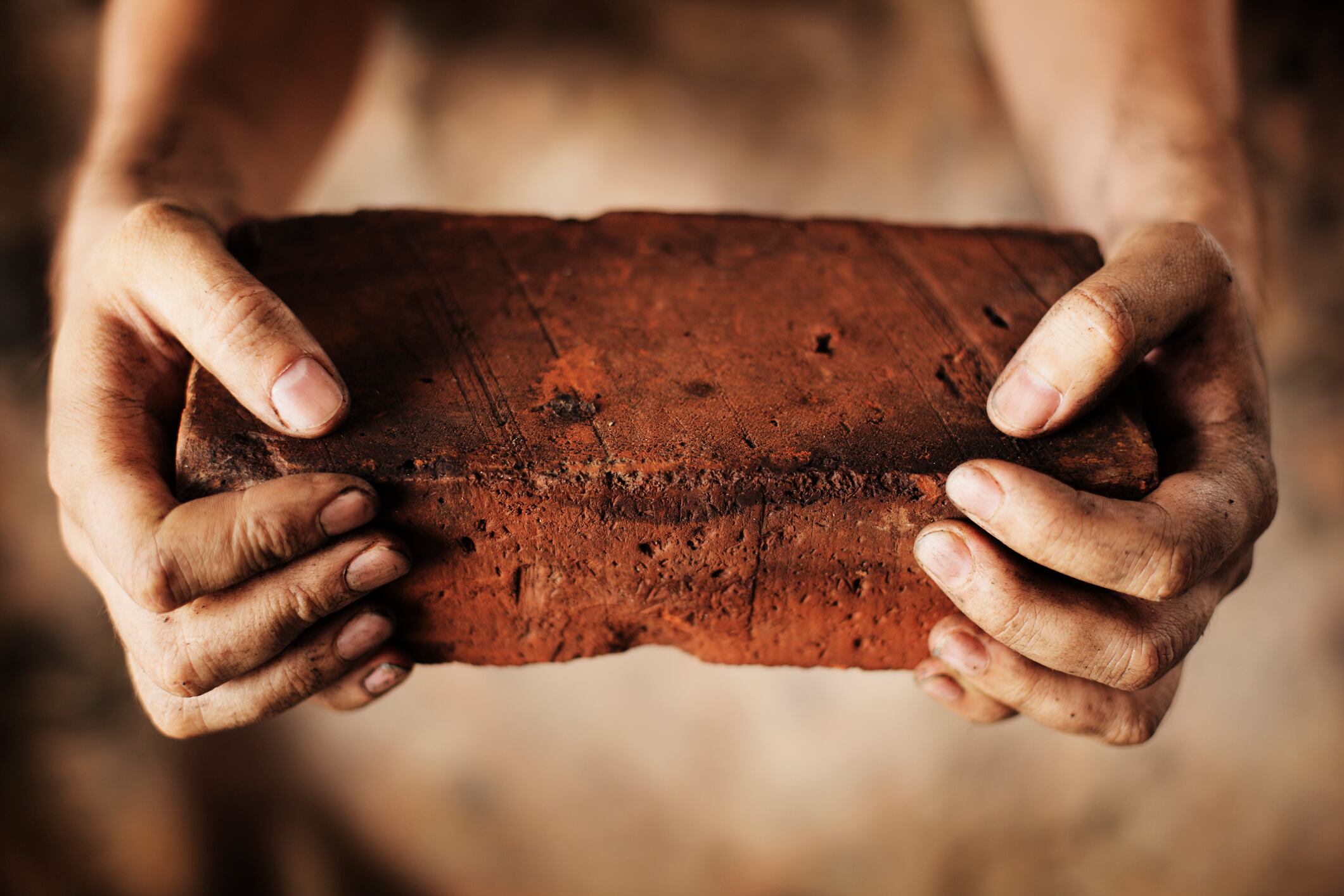Dirty hands holding an old brick