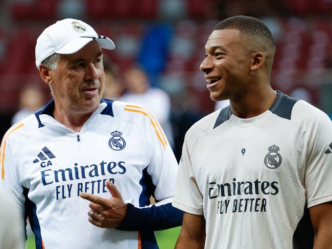 El nuevo delantero del Real Madrid, el francés Kylian Mbappé (d) recibe instrucciones de su entrenador, el italiano Carlo Ancelotti, en el entrenamiento del equipo este martes en Varsovia, en la víspera del partido de la Supercopa de Europa de fútbol. Foto: EFE.