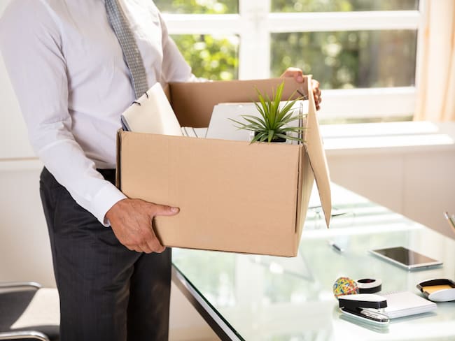 Midsection View Of A Businessman's Hand Holding Belongings In Cardboard Box
