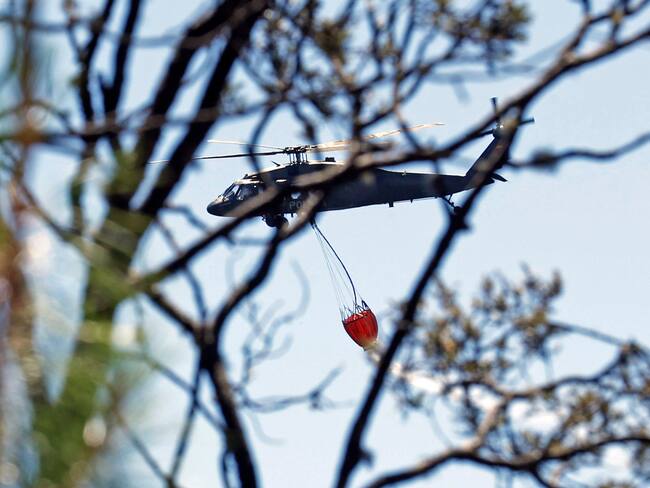 Fotografía de un helicóptero mientras hace una descarga de agua en la zona de un incendio forestal en el cerro El Cable, en Bogotá (Colombia). EFE/ Mauricio Dueñas Castañeda