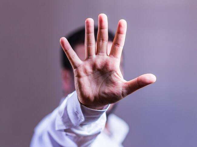 view of a man showing his hand hiding his face - stop gesture