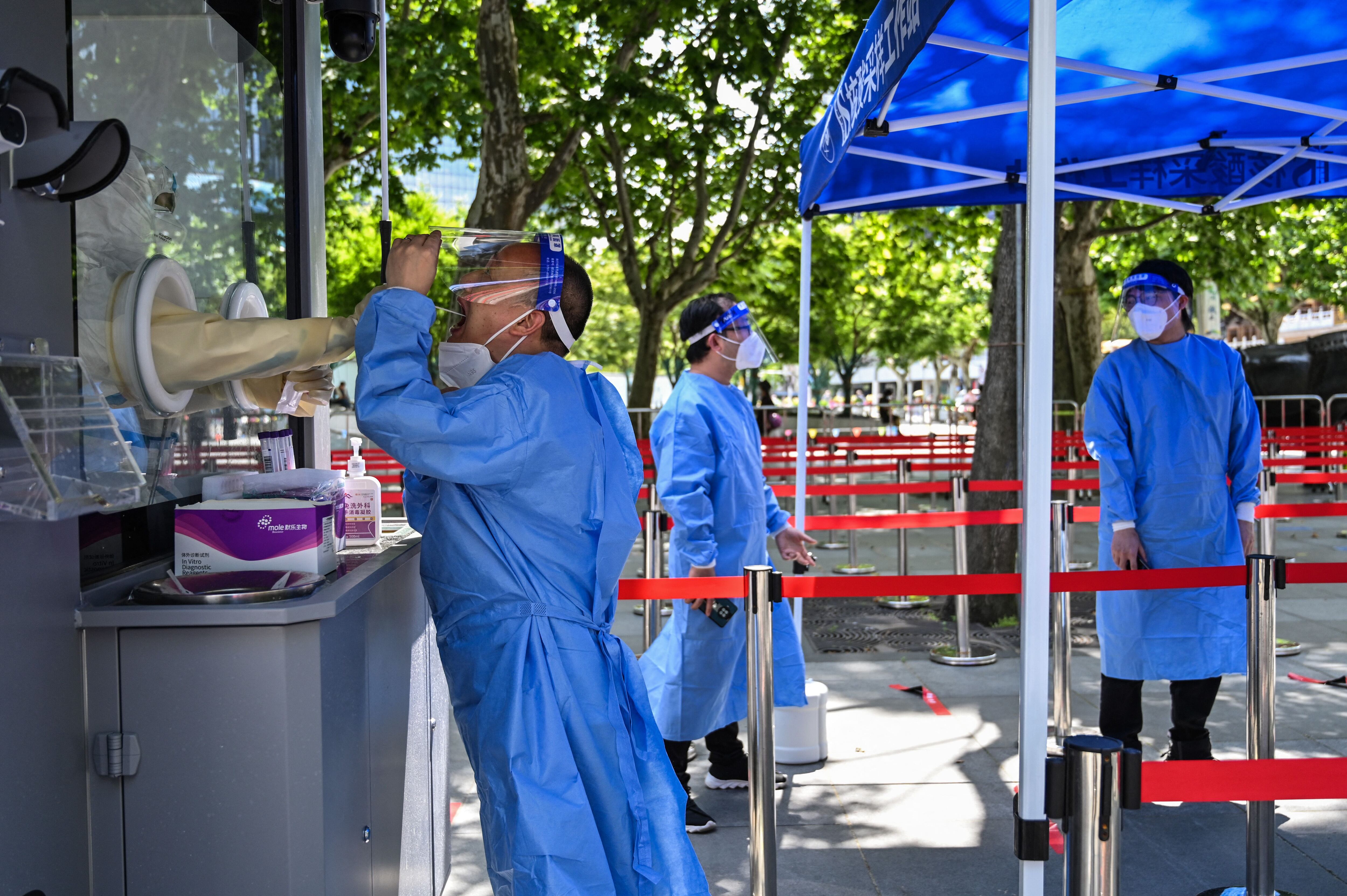 A health worker takes a swab sample from a colleague to be tested for the Covid-19 coronavirus in the Jing'an district of Shanghai on May 31, 2022, as the city prepares to lift more curbs after two months of heavy-handed restrictions. (Photo by Hector RETAMAL / AFP) (Photo by HECTOR RETAMAL/AFP via Getty Images)