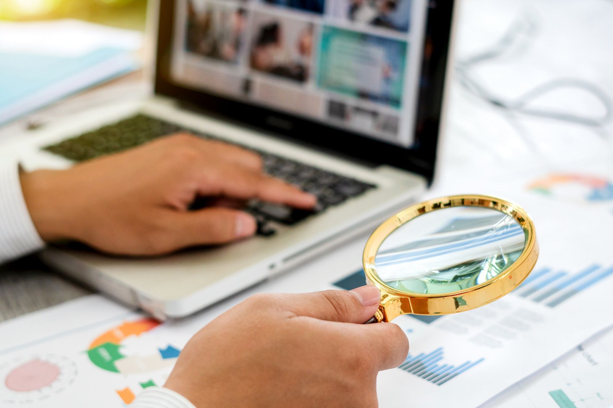 Businessman looking through a magnifying glass to documents