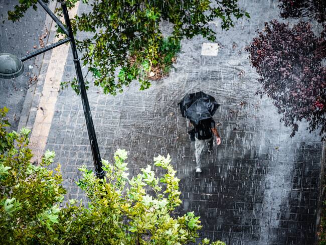 Persona con sombrilla en medio de una fuerte lluvia (Getty Images)
