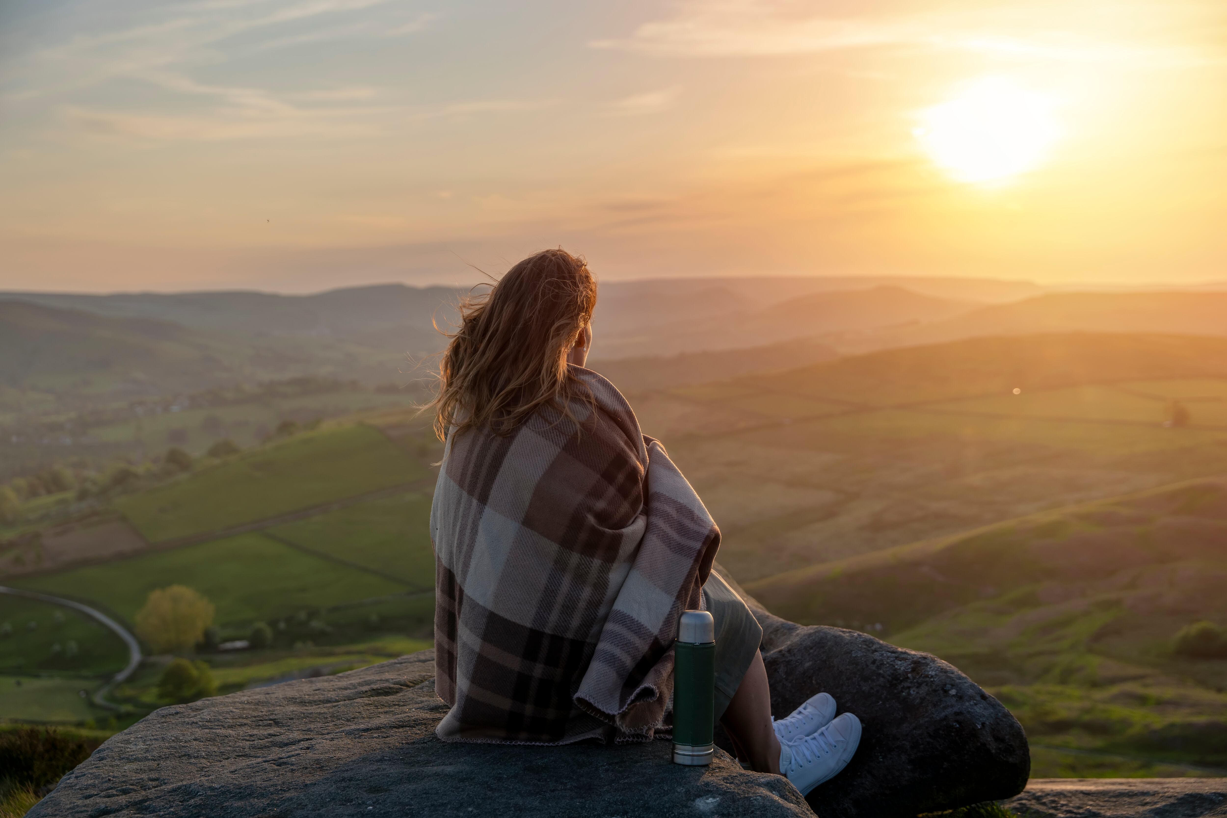 Mujer mirando la apuesta de sol desde el horizonte / Foto: GettyImages