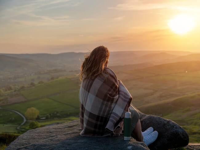 Mujer mirando la apuesta de sol desde el horizonte / Foto: GettyImages