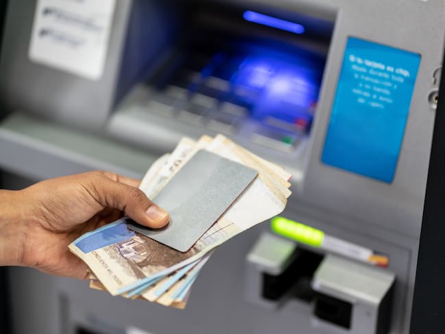 Unrecognizable man holding his debit card and cash after withdrawing from atm - Crad to edit