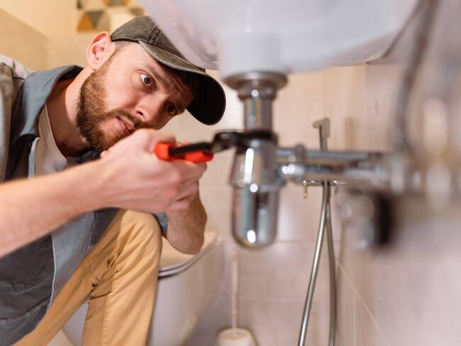 Hombre arreglando fuga del lavamanos dentro de una vivienda / Foto: GettyImages