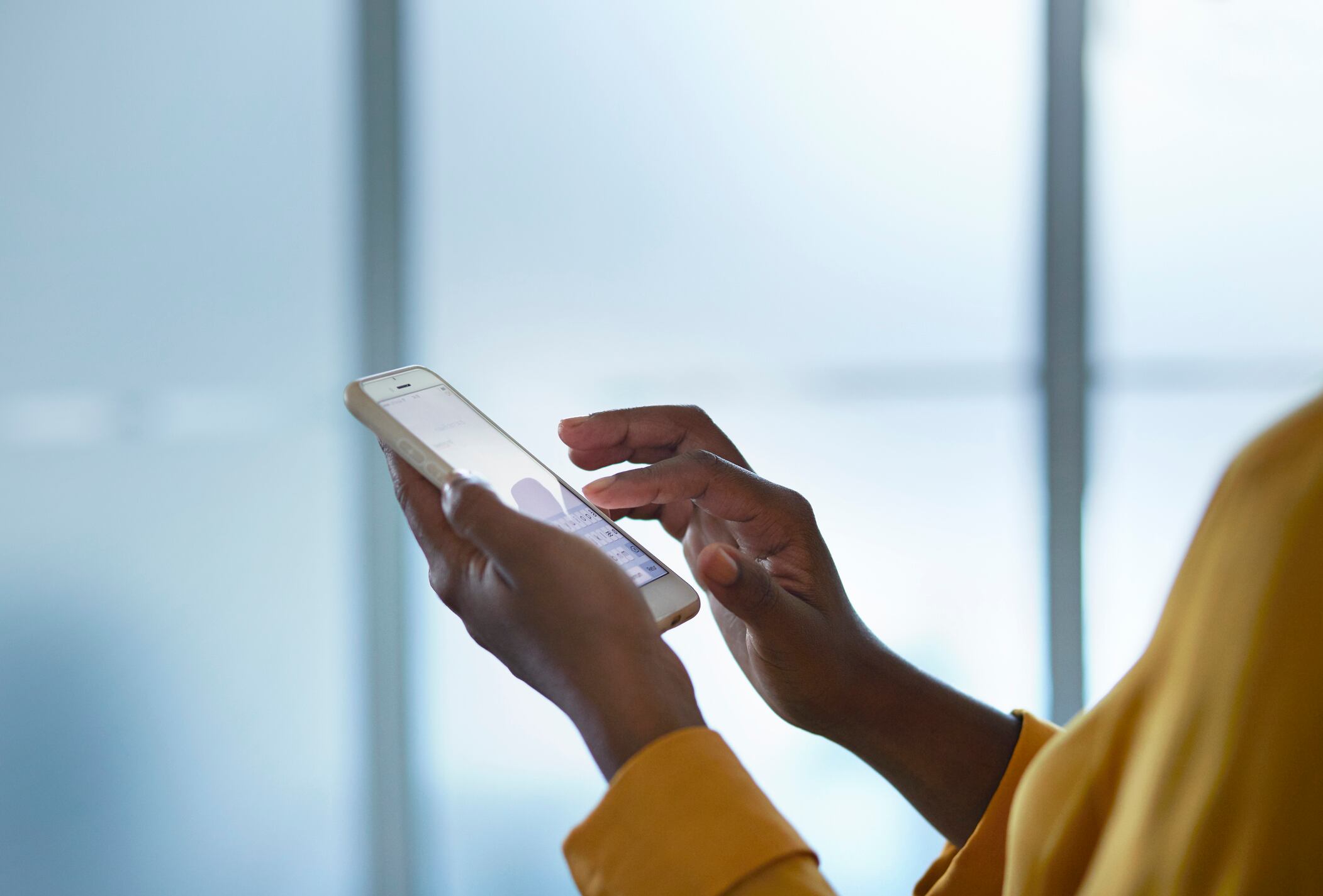 Close-up of businesswomans hands holding phone, in conference room