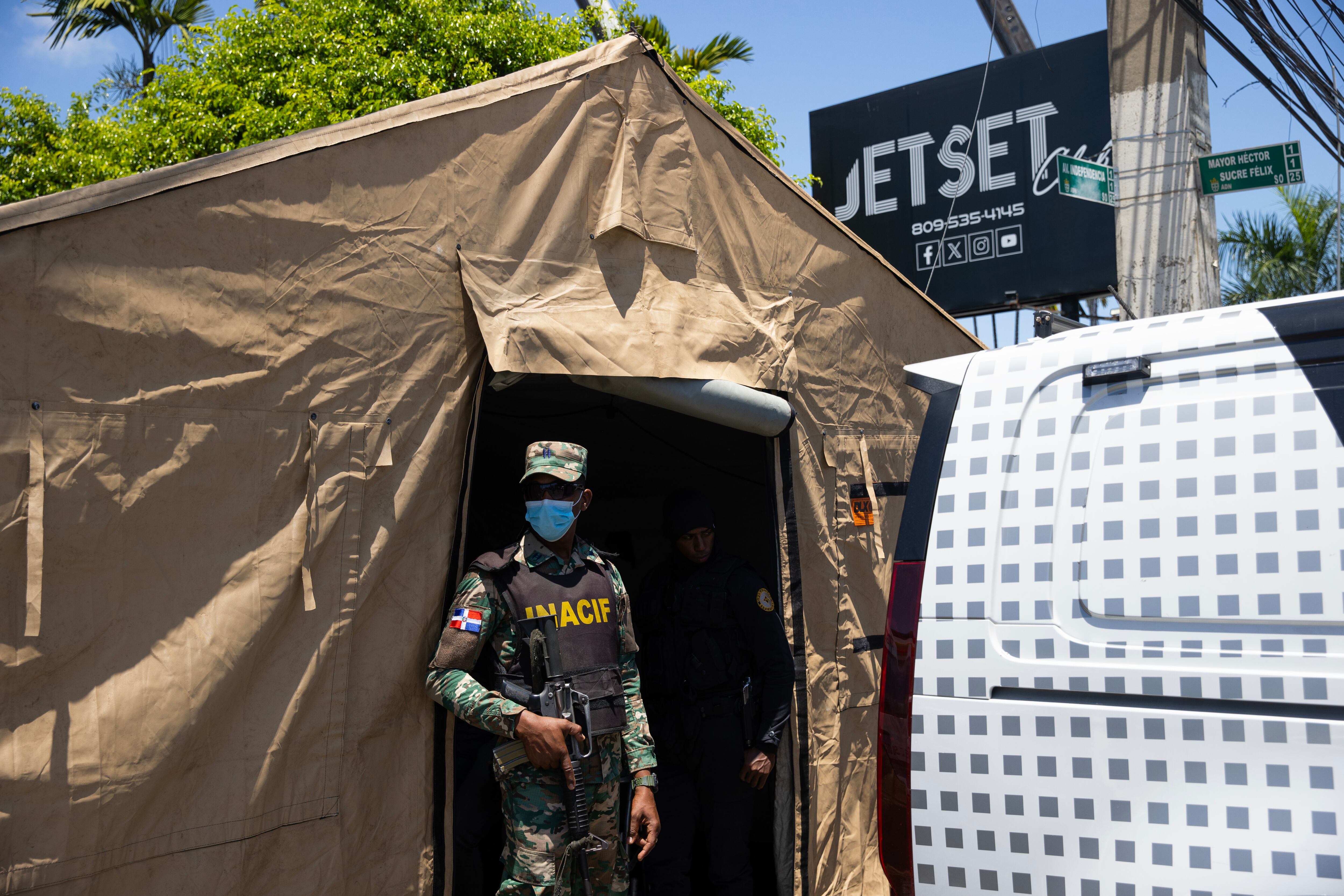 AME7041. SANTO DOMINGO (REPÚBLICA DOMINICANA), 08/04/2025.- Un militar del Instituto Forense vigila en una tienda afuera de la discoteca Jet Set este martes, en Santo Domingo (República Dominicana). Los fallecidos por el desplome del techo de la discoteca Jet Set esta madrugada se elevan ya a 44, mientras continúan las labores de rescate de las personas atrapadas entre los escombros, según los últimos datos facilitados por el Centro de Operaciones de Emergencias (COE). EFE/ Orlando Barría
