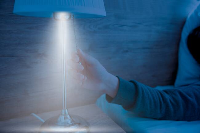 Persona apagando una lámpara antes de dormir (Foto vía Getty Images)