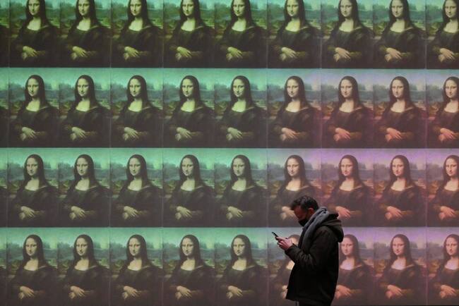Hombre mirando su celular y de fondo tiene un Collage de la pintura de Mona Lisa (Foto de Nicolas TUCAT / AFP) (Getty Images)